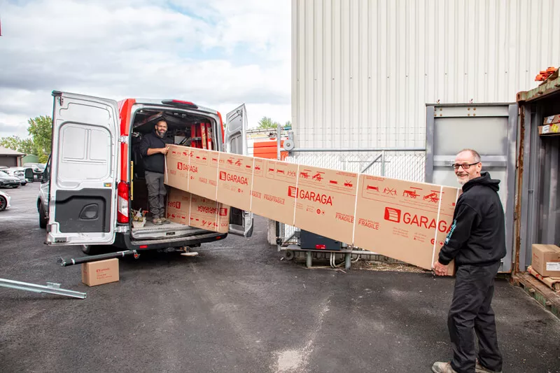 2 installateurs de Portes Exitech mettant les panneaux de la porte de garage dans leur camion.